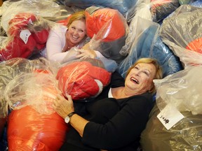 Luke Hendry/The Intelligencer 
Adopt-a-Child chairwoman Ann Earle-Dempsey, left, laughs as volunteer Barb Lea sinks through a pile of bagged winter clothes at the Belleville Police Service building Thursday. This year the program will clothe about 1,100 children from newborns to 12-year-olds, a decrease of about 100 from last year. The campaign got an $11,000 head start from the 100 Women Who Care group and also bought $20,000 of boots.