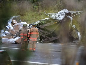 Firefighters observe the wreck of a vehicle involved in Tuesday night's fiery crash on Highway 400. (Mark Wanzel/Postmedia Network)