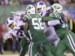 Buffalo Bills running back LeSean McCoy, left, is brought down by New York Jets inside linebacker Darron Lee (58), defensive end Xavier Cooper (75) and another player during the second half of their NFL game Thursday. (AP photo)