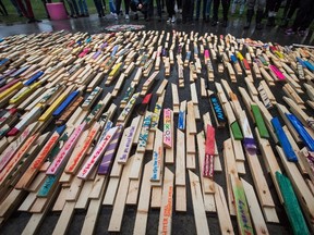 People stand by as 2,224 wooden stakes representing the number of confirmed overdose deaths in British Columbia over the last three years, many of them painted with names of overdose victims, are placed on the ground at Oppenheimer Park, in Vancouver on Friday, September 29, 2017. A decade-long study has found an "alarming rate" of overdose deaths among young Indigenous people in British Columbia. THE CANADIAN PRESS/Darryl Dyck