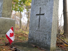 Volunteers placed Canadian flags on the graves of veterans at Cataraqui Cemetery on Tuesday. (Ian MacAlpine/The Whig-Standard)