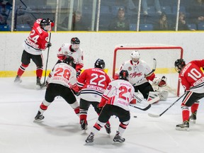 Sarnia Legionnaires forwards Alec DeKoning (No. 22 in red) and Jon Sanderson (No. 10) reach for a loose puck in front of the Leamington net Saturday. The Legionnaires defeated the Flyers 5-3.
Photo courtesy of Shawna Lavoie