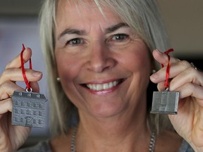 Jan MacDonald, senior projects manager-marketing for Downtown Kingston, holds two of the five pewter ornaments - The Bishop's House/Parish House, left, and Kingston Collegiate - that will be available from Downtown Kingston over the next five weeks. (Ian MacAlpine/The Whig-Standard)