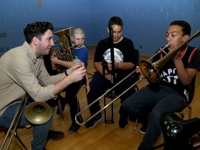 Chris Vincent, left, a trombone player with the band Busty and the Bass, helps J.G. Simcoe Public School students, from left, Dravin Craig, Kazim Evans and Dawson Dobson during a music lesson at the school on Thursday. (Ian MacAlpine/The Whig-Standard)