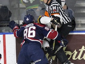 Referee Quincy Evans tries unsuccessfully to avoid being hit as Saginaw Spirit winger Damian Giroux crushes London Knights? Sam Miletic during the first period of their OHL game at Budweiser Gardens on Friday night.  (Derek Ruttan/The London Free Press)