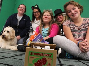 Nicole King with the Sarnia and District Humane Society, left; King George VI principal Tracy Pereira; staff member Jan Moran; and Grade 5 students Luella Smith, front left, and Ella Griffin-Turner, pose behind a coin box featuring a mechanical cat. It's been the drop box for a coin drive at the Sarnia school, raising money for the humane society. There's a theme. The school is trying to help cats "wait less" for care, while welcoming "Weightless" rockers See Spot Run to the school for a concert March 29. That event also features a video message from school alumnus and astronaut Chris Hadfield about weightlessness. Also pictured is labradoodle-wheaten-mix Charlie, 5.  Tyler Kula/Sarnia Observer/Postmedia Network