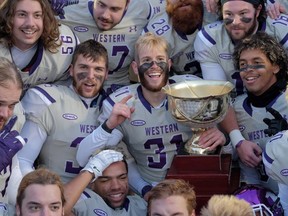 Western Mustangs players celebrate with the trophy after their dominating 81-3 win over the Acadia Axemen in the Uteck Bowl on Saturday. (THE CANADIAN PRESS)