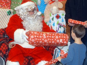 Weston Rabideau, 3, receives a gift from Santa thanks to the efforts of volunteers and local businesses which donated money to purchase Christmas gifts for the kids who met with Santa earlier in the day at the Knights of Pythias breakfast with Santa event.