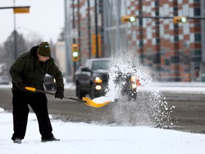Chris Elliot from Local Lous on 16 Ave. shovels snow as Calgarians woke up to a blast of winter with more snow in the forecast on Thursday November 2, 2017. Darren Makowichuk/Postmedia Network