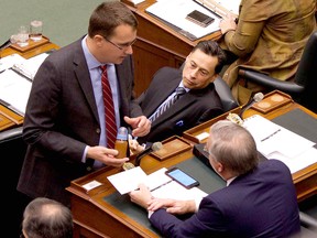 Lambton-Kent-Middlesex MPP Monte McNaughton, left, delivered a bottle of dirty water from a water well located in the North Kent 1 Wind project area, to Minister of Environment and Climate Change Chris Ballard during question period at Queen's Park in Toronto, Ont., on Tuesday, November 21, 2017. Brad Duguid, Minister of Economic Development and Growth watched the exchange. (Handout)