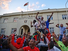 Zimbabweans celebrate outside the parliament building immediately after hearing the news that President Robert Mugabe had resigned, in downtown Harare, Zimbabwe Tuesday, Nov. 21, 2017. (AP Photo/Ben Curtis)