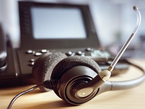 This stock photo shows a call centre headset sitting on an office desk next to a work phone. (Getty Images)