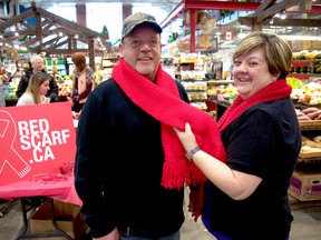 Fran McKeown, a volunteer co-ordinator with Regional HIV/AIDS Connection (right), ties a red scarf around volunteer Gerry Graham at Covent Garden Market. HIV/AIDS Connection has been handing out hand-made red scarves to raise awareness of their work for the past five years. More recently, the scarves have become a fundraising item leading up to AIDS Awareness Week. (CHRIS MONTANINI\LONDONER\POSTMEDIA NETWORK)