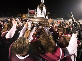 Jubilant South Lions players surround the prized trophy as the celebrate their WOSSAA senior football victory over CCH Crusaders at TD Stadium in London Thursday. The Lions beat CCH 14-1 to claim the title. In the junior final, played earlier in the day, Parkside Stampeders defeated the Crusaders 35-7. (MIKE HENSEN, The London Free Press)
