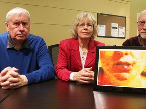 Michael Hurley, left, with the Ontario Council of Hospital Unions, poses with researchers Margaret Keith and Jim Brophy, and a photo of a battered health-care worker, Thursday at the Sarnia Library. They're touring Ontario communities, drawing attention to their study about the violence and suppression faced by health-care workers in the province. (Tyler Kula/Sarnia Observer)