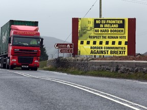 This file photo taken on January 30, 2017 shows traffic crossing the border into Northern Ireland from the Irish Republic next to a poster protesting against a hard brexit near Dundalk on January 30, 2017. The fallout of Brexit is not only about trade and the economy, Brexit is also about keeping the peace, a peace that must not be taken for granted two decades after the Good Friday agreement erased the border between British-ruled Northern Ireland and the Republic of Ireland, but still struggles to bridge communities. (AFP PHOTO / Paul FAITH)