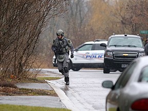 A Kingston Police tactical officer runs to a home on Graceland Avenue as a standoff ensued. Elliot Ferguson/The Whig-Standard