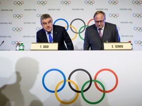 International Olympic Committee, IOC, President Thomas Bach from Germany, left, and Samuel Schmid, President of the IOC Inquiry Commission and former President of Switzerland, right, take their seats as they arrive for a press conference after an Executive Board meeting, in Lausanne, Switzerland, Tuesday, Dec. 5, 2017. Russian athletes will be allowed to compete at the upcoming Pyeongchang Olympics as neutrals despite orchestrated doping at the 2014 Sochi Games, the International Olympic Committee said Tuesday. (Jean-Christophe Bott/Keystone via AP)