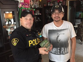 Carlos Teixeira, with Lambton OPP, delivers a copy of the Trent Severn album Portage to Travis Peters at his home at the Pikangikum First Nation in remote northwestern Ontario. A song on the album, You Are Enough, was inspired by Peters. Teixeira, who was visiting the community recently for work, is a long-time friend of Emm Gryner, a member of the southwestern Ontario-based folk trio. (Handout)