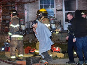 A man covered with a blanket to stay warm heads to a police car to give a statement at the scene of a fire on Egerton Street on Friday December 8, 2017. (MORRIS LAMONT, The London Free Press)