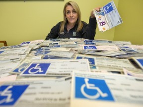 Annette Drost, London?s parking boss, shows off hundreds of confiscated handicapped parking permits. The one she?s holding is stiffened with a backing made from Cheerios and Heineken boxes ? the owner claimed it came from the Ontario government that way. (MIKE HENSEN, The London Free Press)