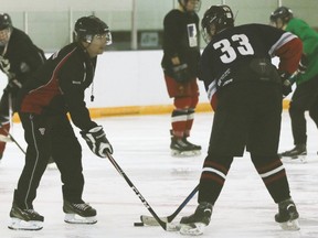 County Central High School hockey program teacher Don Monts, left, and student Darien Sager practise puck handling skills at the Vulcan District Arena.