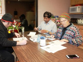 Sarnia-Lambton Amnesty Action Group members Chris Temple (left), Subash Prasad (centre) and Thea DeGroot write letters of hope to imprisoned activists on Dec. 6. Carl Hnatyshyn/Postmedia Network