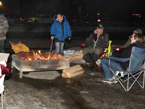 Homeless for 24 participants warm themselves around a fire in the Family Worship Centre parking lot on Dec. 9 (Peter Shokeir | Whitecourt Star).