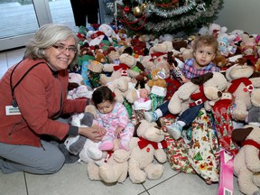 Helen Mabberly, manager of Family and Community Health at Kingston Community Health Centres with Hanna Mohammed, three months and Razan Ellawindy, two years-old, as they sit amongst almost 300 stockings and teddy bears at the Kingston Community Health Centres on Monday December 11 2017. Ian MacAlpine/The Whig-Standard/Postmedia Network
