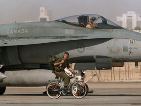 A Canadian CF-18 pilot prepares to take off, as a member of the ground crew pedals his bicycle past the jet in Qatar, January 20, 1991 during the Gulf War. THE CANADIAN PRESS//Fred Chartrand