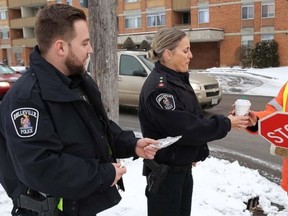 TIM MEEKS/THE INTELLIGENCER
Constable Zach Desousa and Inspector Sherri Meeks of the Belleville Police Service deliver a cup of hot chocholate and a cookie to crossing guard Bob Reid at the intersection of Palmer Road and Harder Drive Friday morning. Belleville police, with the support and generosity of Starbucks, has been engaging in a holiday surprise for all crossing guards throughout the city this week. Every morning, police officers have been hand delivering a hot chocolate and cookie to six crossing guards at various intersections throughout the city as a small gesture in appreciation for keeping all of our children safe throughout the year; no matter the weather.
