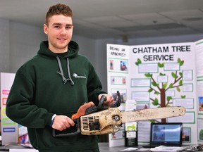 Ursuline College Chatham student Dylan Buchanan holds up a chainsaw in front of his co-op presentation about his experiences working with the Chatham Tree Service during the school's co-op career day on Wednesday.