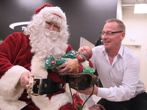 Gino Donato/Sudbury Star/Postmedia Network

Santa Claus was on hand at the The Car Lot Etc to help distribute pyjamas to children and families from Our Children Our Future on Thursday. Santa holds three-week-old William Booker as Phil Mullin of The Car Lot helps hand out gifts. The Car Lot donated 150 pyjamas at the event.