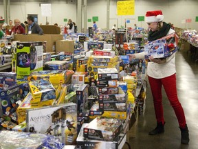 Volunteer Cassandra Gilbert collects toys for 10-year-olds as she helps assemble gift bags for the Salvation Army hamper and toy drive at the Western Fair?s Progress Building on Friday. (MIKE HENSEN, The London Free Press)