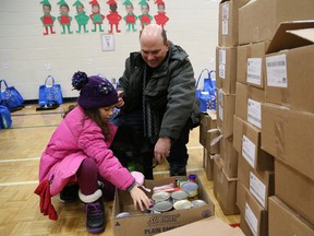 Jillian O'Connor, 7, and her dad, Kevin, prepare Christmas baskets at an event hosted by Club Richelieu Les Patriotes in Sudbury, Ont. on Saturday December 16, 2017. A total of 148 families and individuals in need, received the baskets containing food items. John Lappa/Sudbury Star/Postmedia Network