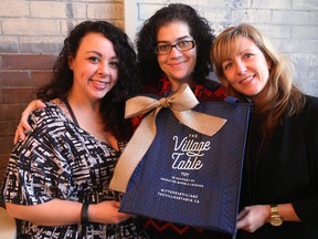 Jennifer Watts, left, and Sarah Campbell, executive director of Meals on Wheels, share their enthusiasm with Pillar non-profit network executive director Michelle Baldwin, right, with one of their Village Table bags. Baldwin has used the program. ?I believe in Meals on Wheels and I get to deliver meals to people in the community l love and let them know I care about them,? she said. (MIKE HENSEN, The London Free Press)