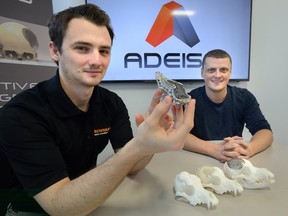 Matt Parkes, left, and Tom Chmiel of the ADEISS medical devices company at the Western Research Park show off a titanium snout implant, also seen at right, that they fabricated with a 3-D printer for use in a dog?s surgery. (MORRIS LAMONT, The London Free Press)