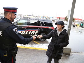 JASON MILLER/The Intelligencer
Const. Paul Fyke gets a cash donation from Mary Maracle during a food drive at Marc's No Frills.