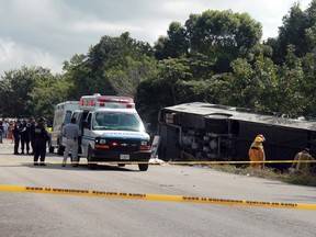 An ambulance sits parked next to an overturned bus in Mahahual, Quintana Roo state, Mexico, Tuesday, Dec. 19, 2017. (Novedades de Quintana Roo via AP) ORG XMIT: MXEV103
