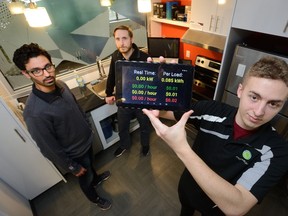 Software engineers Salim Fgaier, left, Curtis Conway and Connor Graham display a tablet that monitors power usage in real time at a demonstration kitchen that is part of the innovation centre at London Hydro on Thursday. (MORRIS LAMONT, The London Free Press)