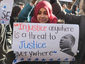 Muslim girl holds a sign (with a quote from Martin Luther King Jr.) during a protest in downtown Toronto on January 30, 2017. (Getty Images)