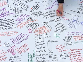 Mourners continue to place flowers and candles and sign a community banner in Springer Market Square in memory of Gord Downie in Springer Market Square on Oct. 18. (Elliot Ferguson/The Whig-Standard/Postmedia Network)