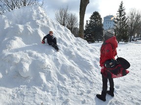 Sharlene Sterkenburg watches as her step-son Tyson Antoine, 8, slides down a giant mound of snow in Victoria Park in London Ontario on Tuesday January 2, 2018. The snow scraped from both downtown public skating rinks was piled up to create a sliding hill for kids attending new year's eve celebrations. (MORRIS LAMONT/THE LONDON FREE PRESS)