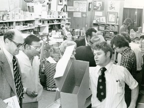 Cliff Maxwell, right, "tries to keep up with the customers in his camera shop" in a 1975 Times-Journal photo of a downtown surprise sale. (Times-Journal photo // Courtesy of Elgin County Archives)