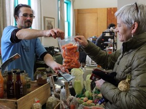 Susan Shoniker purchases carrots from Tim Lyon and the Main St. Market at the Memorial Centre Farmers’ Market's Winter Market in Princess Street United Church’s community hall on Sunday. (Steph Crosier/The Whig-Standard/Postmedia Network)