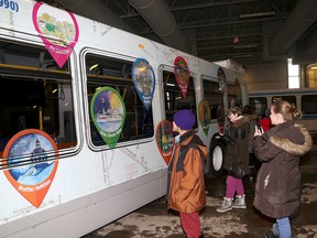 Students look at their art work after Kingston Transit unveiled art from students in the Limestone District School  Board Arts focus program wrapped on a city bus on Monday. (Ian MacAlpine/The Whig-Standard)