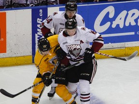 Kingston Frontenacs Brett Neumann battles for the puck with Guelph Storms' Nate Schnarr and Cedric Ralph during the first period of Ontario Hockey League action at the Rogers K-Rock Centre in Kingston, Ont. on Friday, January 12, 2018. JULIA MCKAY/Whig-Standard/Postmedia Network