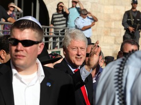 Former US president Bill Clinton (C) waves upon his arrival at the Western Wall in Jerusalem's Old City for a visit to Judaism's holiest site on November 15, 2009. Clinton said ahead of the opening of a museum and centre in Tel Aviv dedicated to Israel's assassinated prime minister Yitzhak Rabin on November 14 that he believes there would have been a comprehensive peace in the Middle East a decade ago if Rabin had not been assassinated. AFP PHOTO/SHAI COHEN