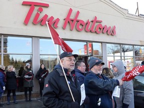 Members of Ontario Federation of Labour protest outside a Tim Hortons Franchise in Toronto on Wednesday January 10, 2018. Protesters angered by some Ontario Tim Hortons franchisees who slashed workers' benefits and breaks after the province raised minimum wage will demonstrate across the country tomorrow. (THE CANADIAN PRESS/Chris Young)