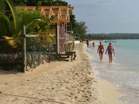 In this Sept. 14, 2014 photo, sunbathers walk along resort-lined crescent beach in Negril in western Jamaica. Canadian sun seekers in Jamaica are being urged to ``exercise a high degree of caution'' following a spate of violent crime in the popular winter getaway. THE CANADIAN PRESS/AP-David McFadden